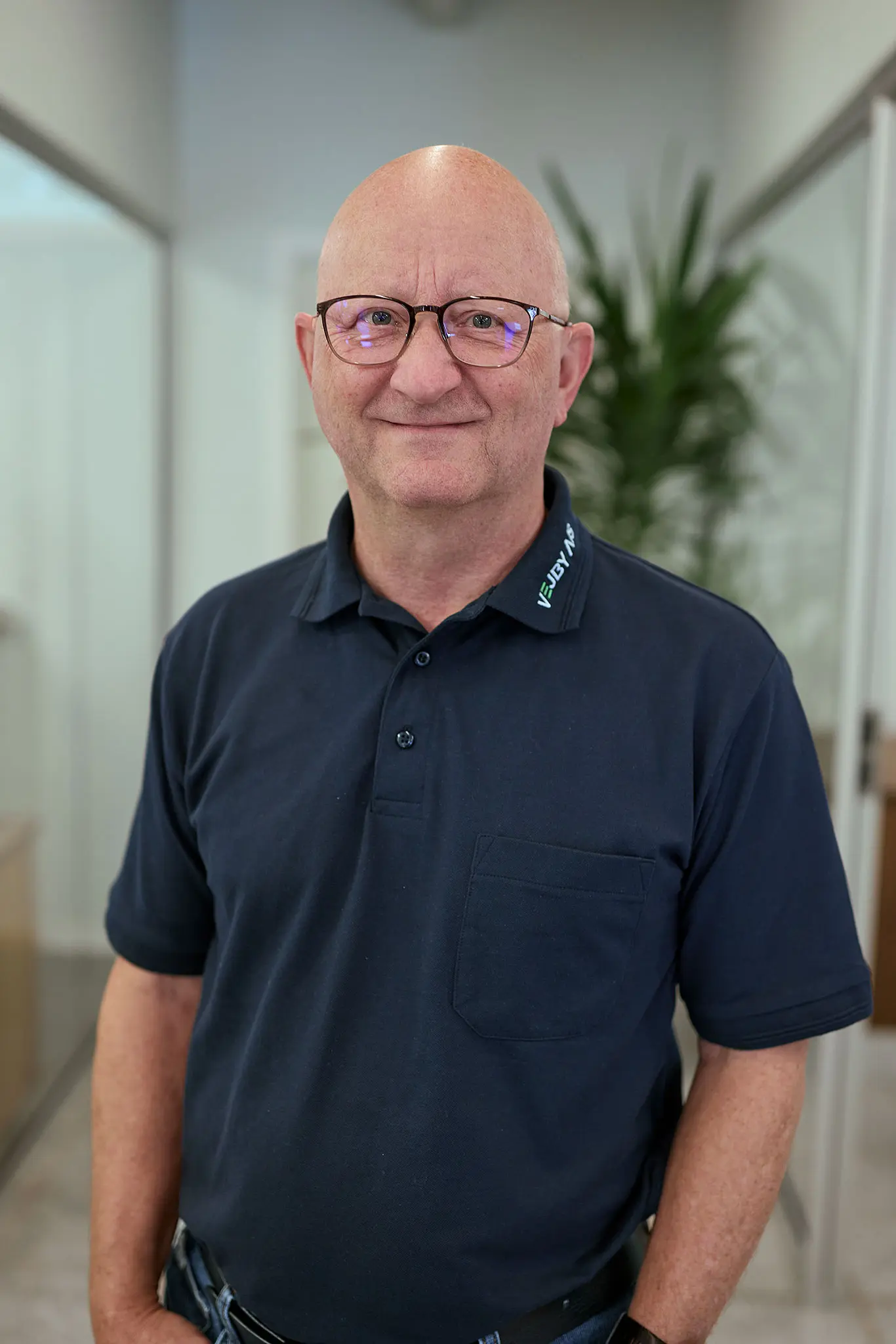 Portræt af Lasse Pallesen fra Vejby A/S i mørkeblå polotrøje og med briller.