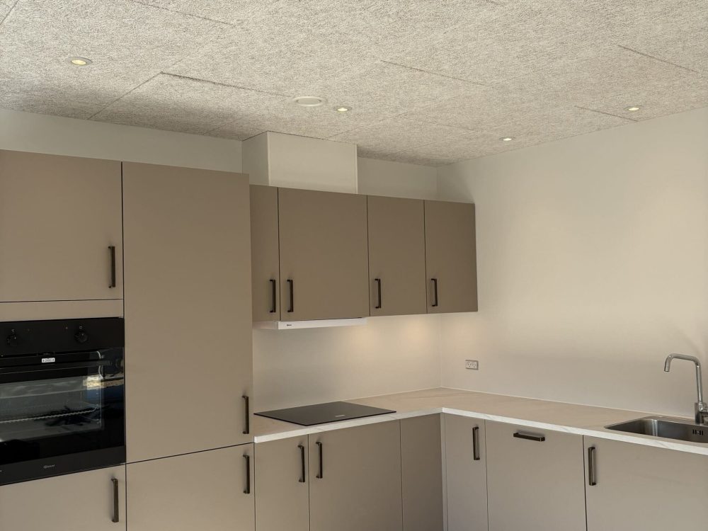 Moderne beige køkken med indbygget ovn, kogeplade og spots installeret af Vejby A/S i Villaparken, Balling.