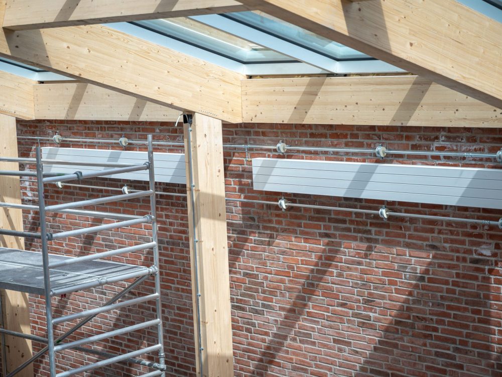 VVS-installation med hvide varmepaneler på murstensvæg i et nyt byggeri udført af Vejby A/S.